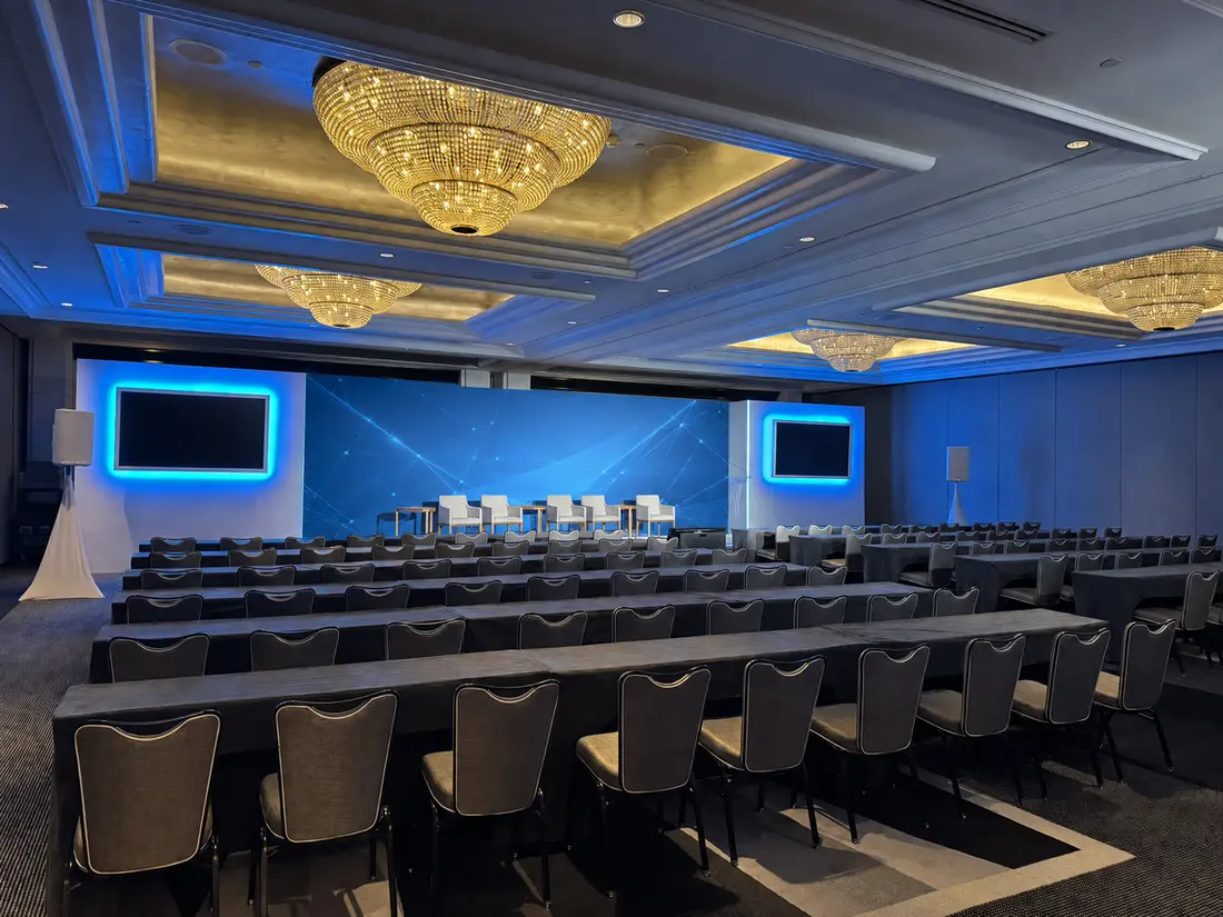 Ballroom prepared for a corporate event with stage screens, audience seating, and managed event connectivity